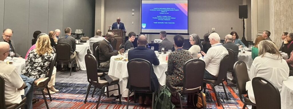 Ronald Crutcher, president emeritus of the University of Richmond, speaks to a room of seated participants from a podium.