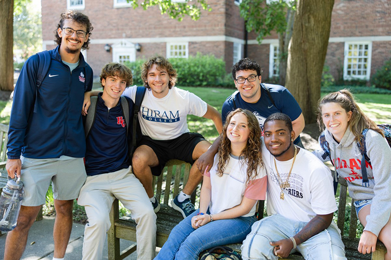 seven students pose outside on a bench
