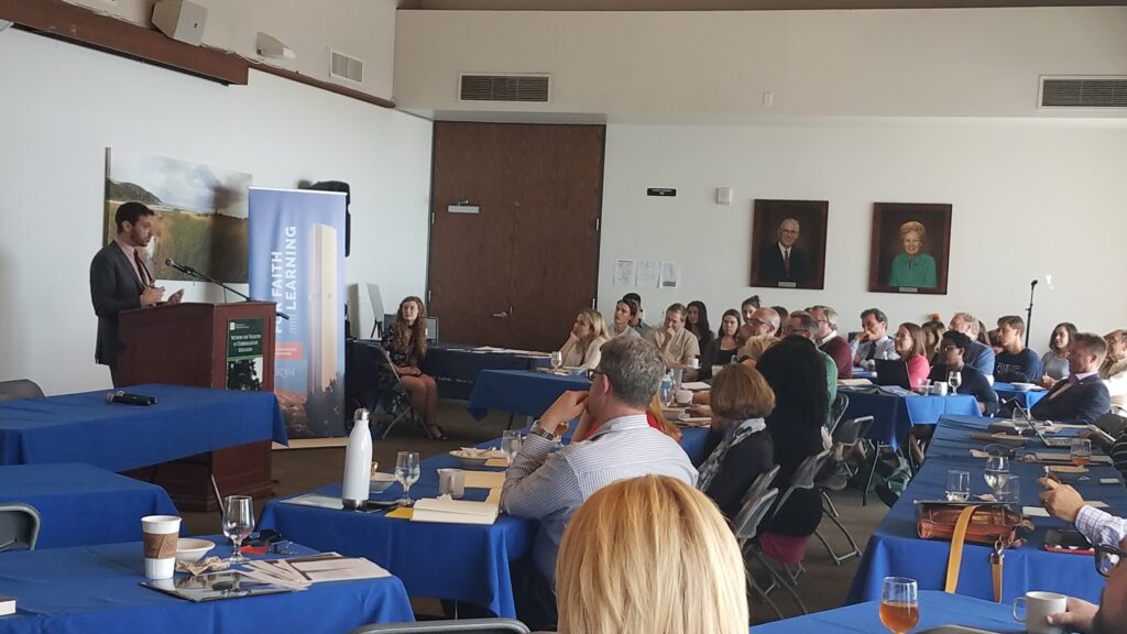 Participants of a NetVUE gathering listening to a speaker standing at a podium.
