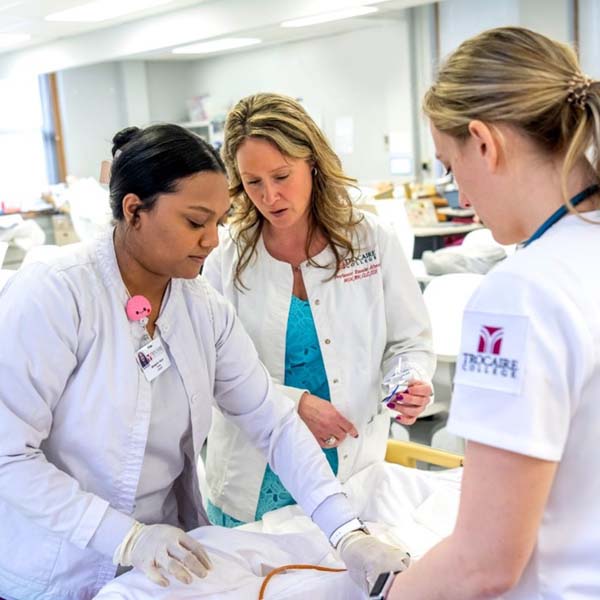 A professor instructs two students in a medical lab