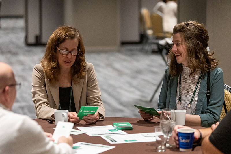 Participants read prompts on conversation cards while seated at roundtables