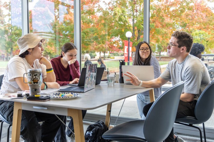 Four students seated at a table with laptops