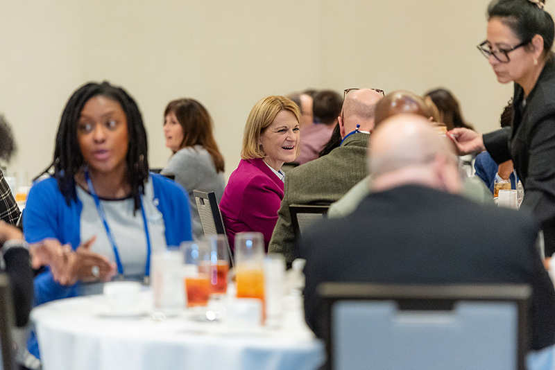 Participants speak to one another seated at roundtables