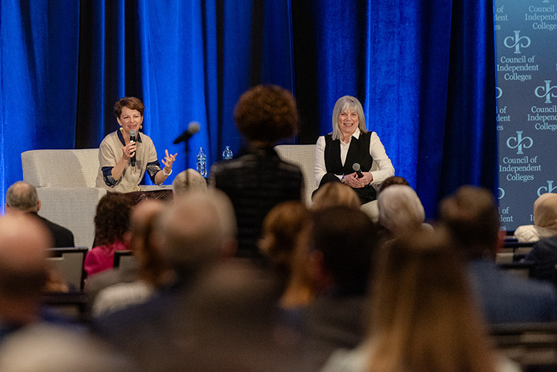 Seated on stage with Marjorie Hass, Amanda Ripley answers a question from a participant standing at a microphone