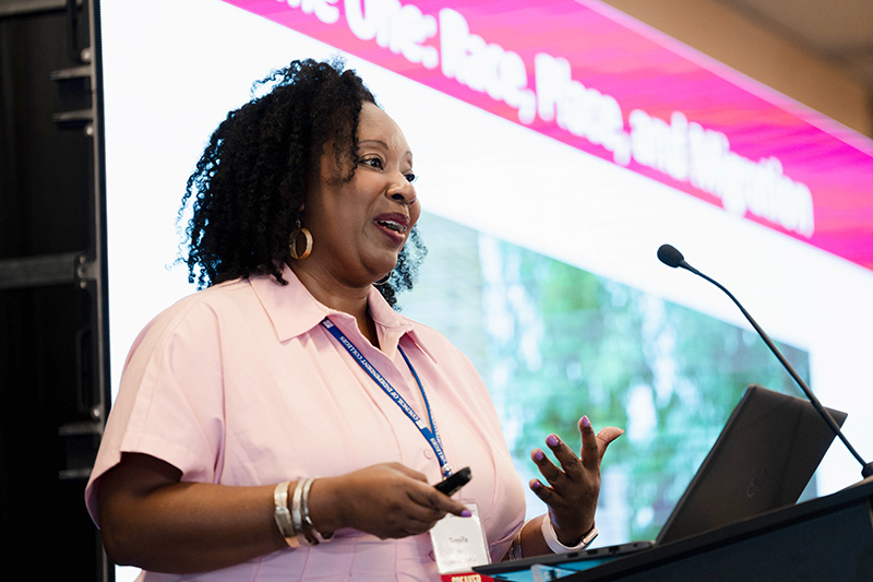 Tennille N. Allen presents from podium with presentation screen in background