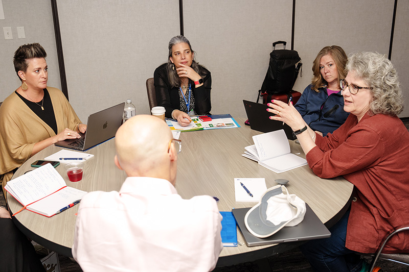 Participants and presenters speak while seated at a roundtable