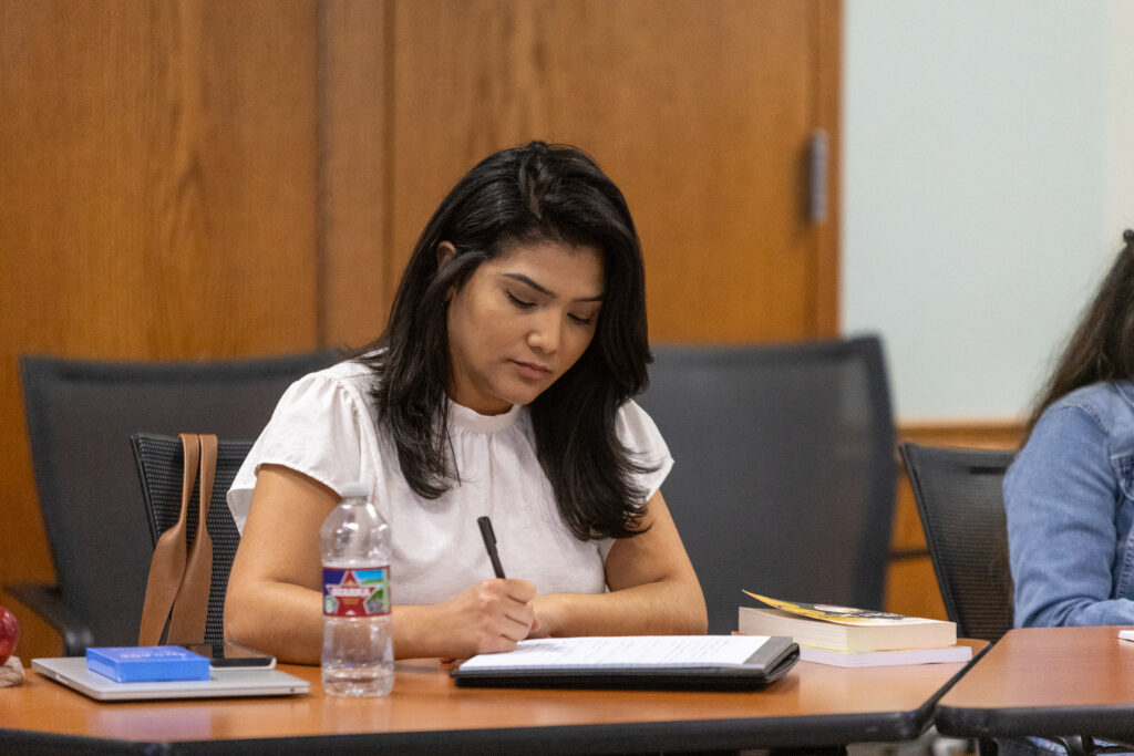 Woman seated at desk writing in notepad