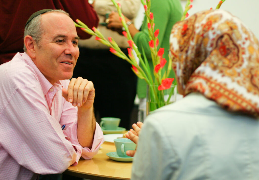A man seated at a table in discussion with a colleague