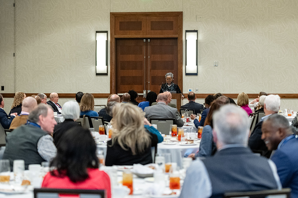 Session speaker presents from podium to participants seated at roundtables
