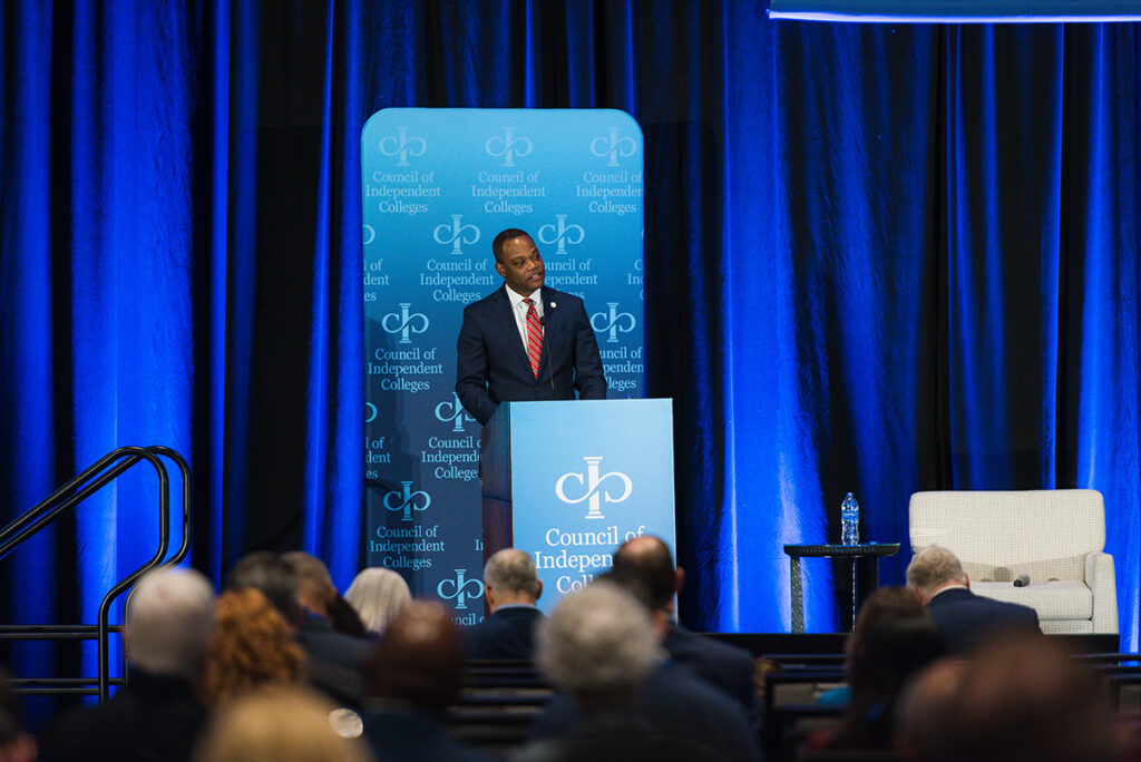 College president introducing plenary speaker from podium